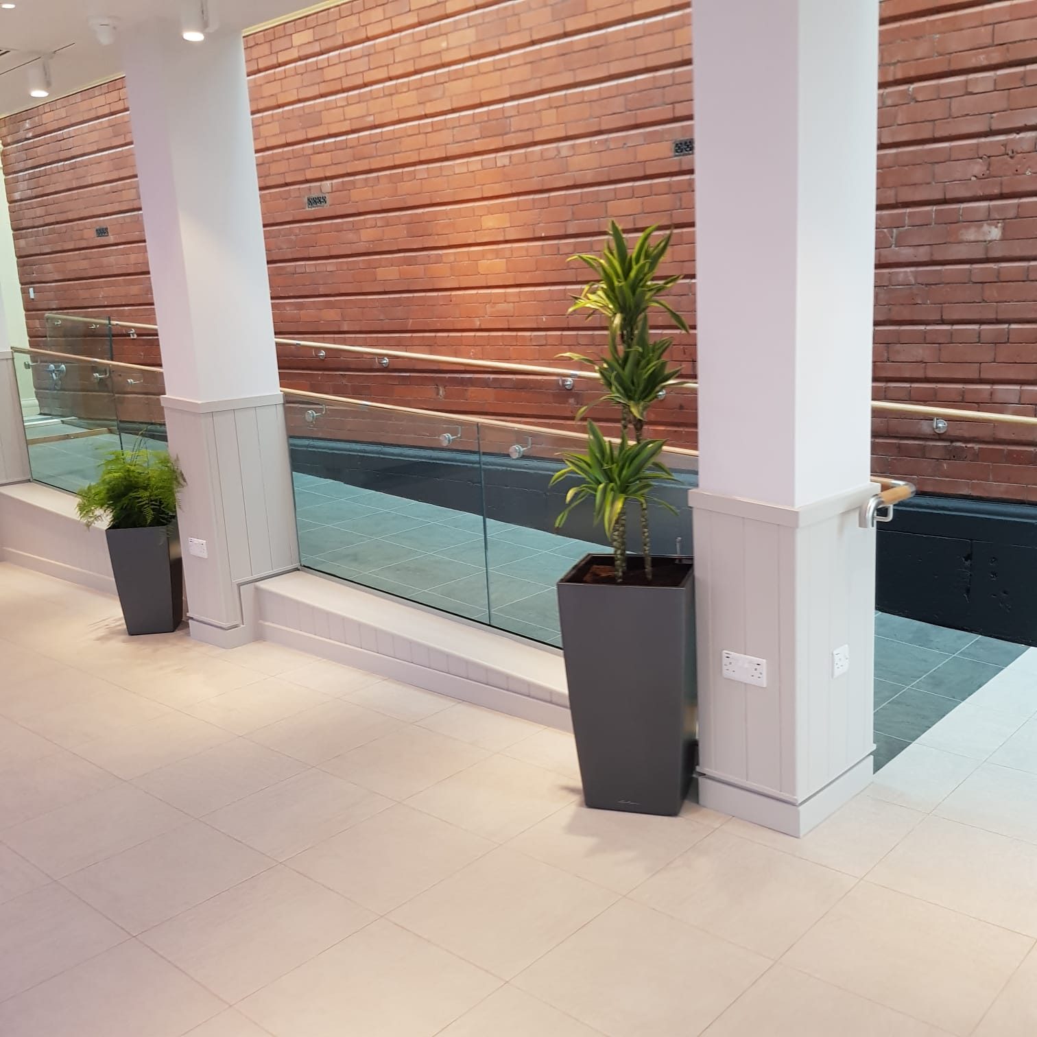 Glass balustrade with timber-capped handrail on a brick wall in a converted building