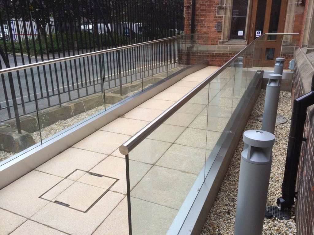 External glass balustrade and stainless steel handrail alongside a paved access ramp