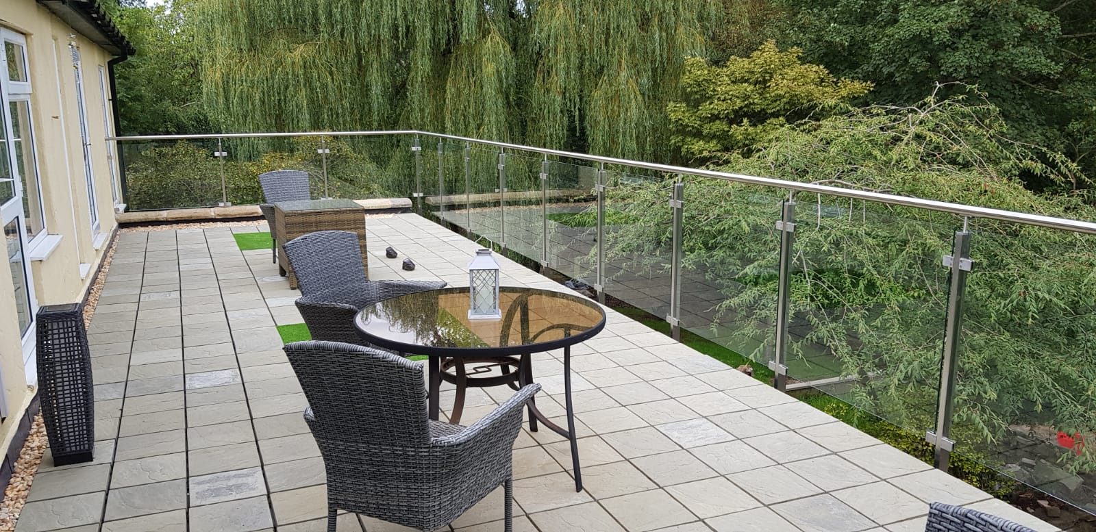 Frameless glass balustrade with stainless posts and top rail edging a raised garden terrace