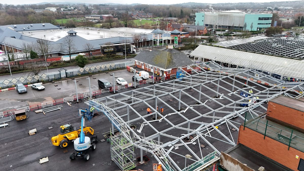 Steel portal frame canopy under construction with cherry pickers and site plant on an active build
