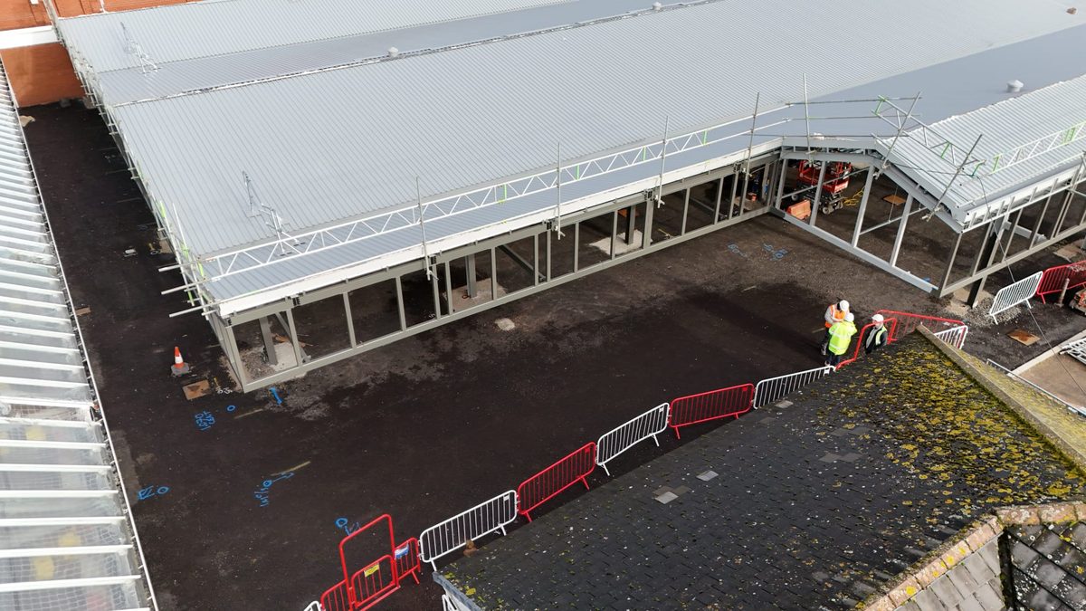 Low angle view of a steel canopy eaves with scaffold access and installers working at height