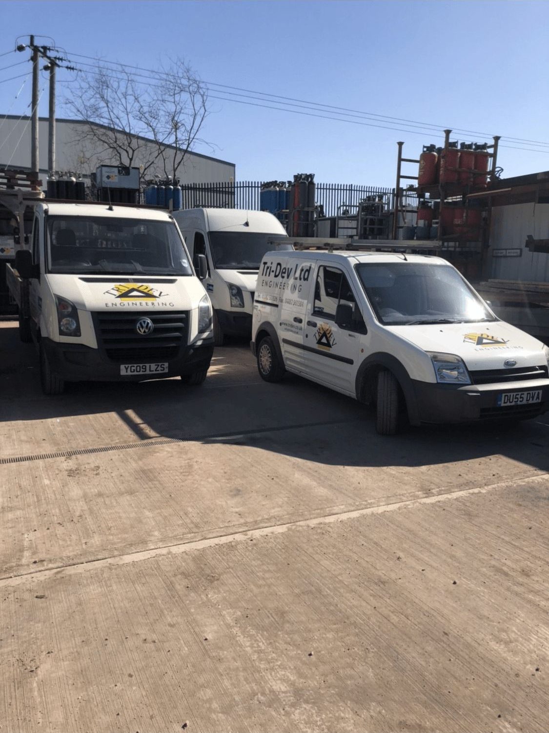 Two Tri-Dev Ltd liveried vans parked in the works yard alongside gas cylinder racks