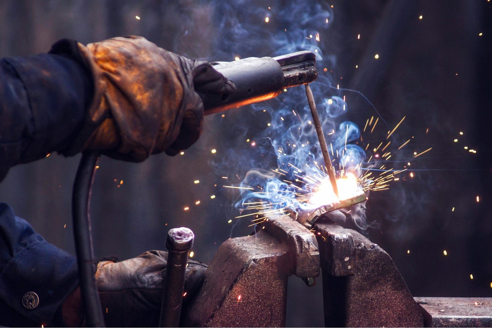 Close-up of stick welding, with the electrode striking an arc and sparks flying from the joint